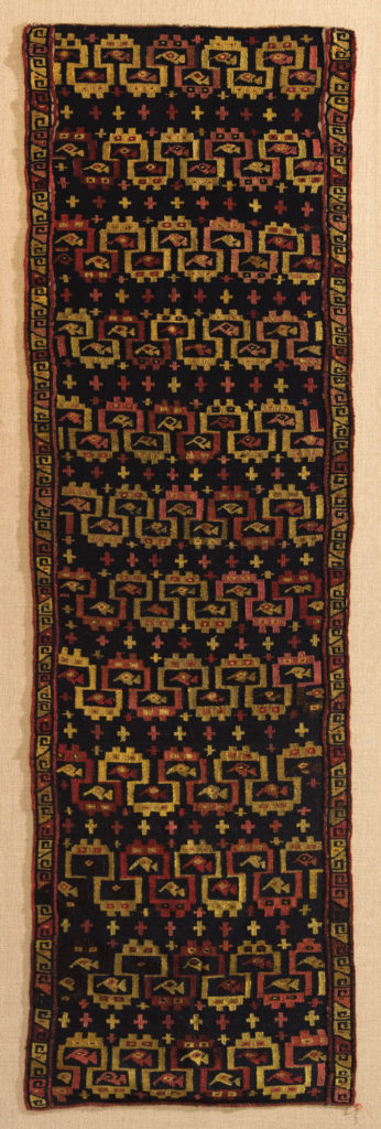 A textile decorated with a series of geometric, abstract feline heads. (Chancay)