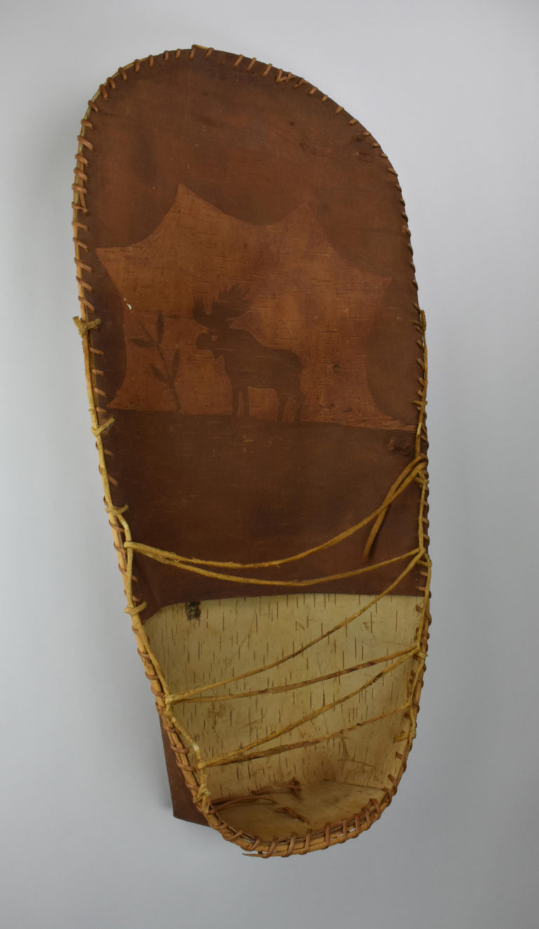A small, birch bark cradle decorated with an image of a moose