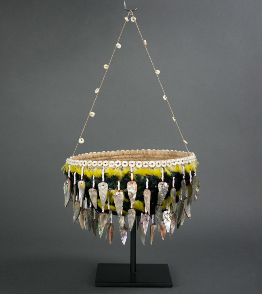 A basket adorned with shells, glass beads, and feathers