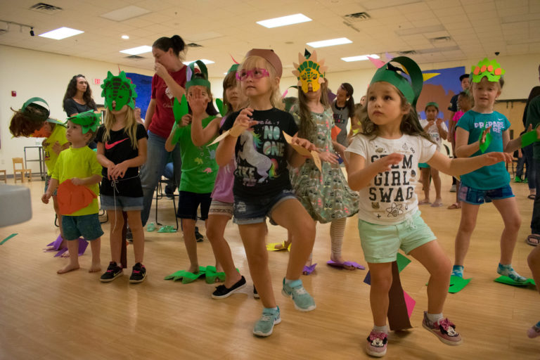 Children dressed up as dinosaurs doing the "dinosaur dance"