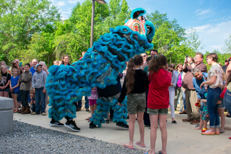 Lion dancers performing for a crowd of people on a sunny day